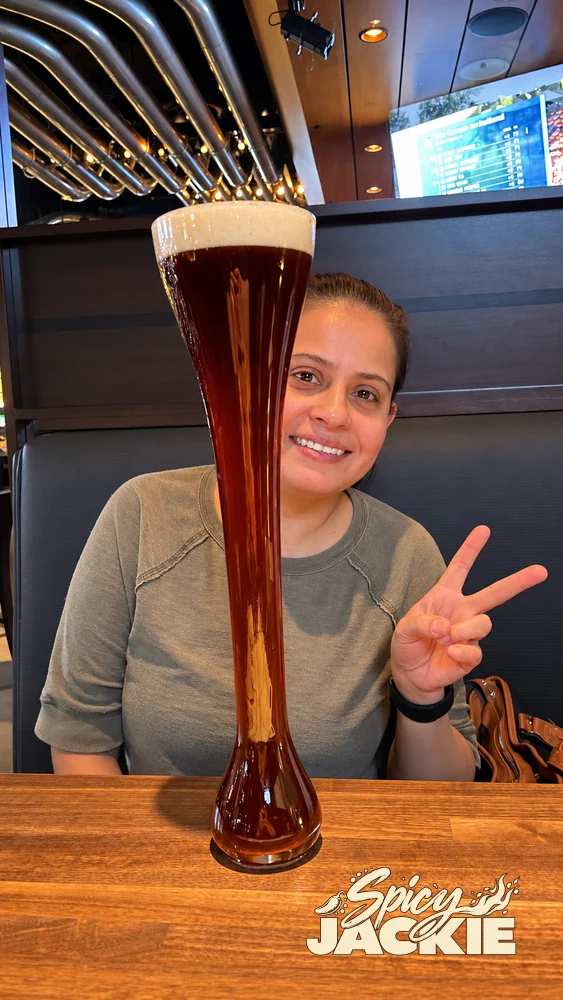 Jackie smiling behind a tall glass of beer at a wooden table