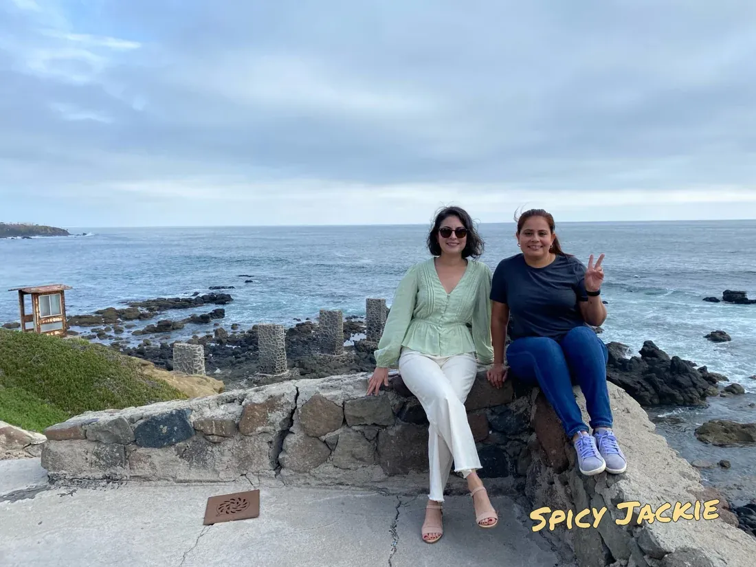 Jackie and a companion sitting together beside the ocean