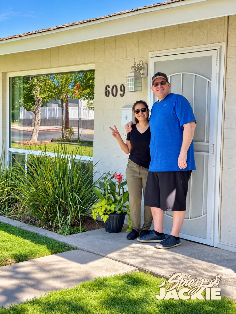 Jackie and a companion standing outside a light-colored house