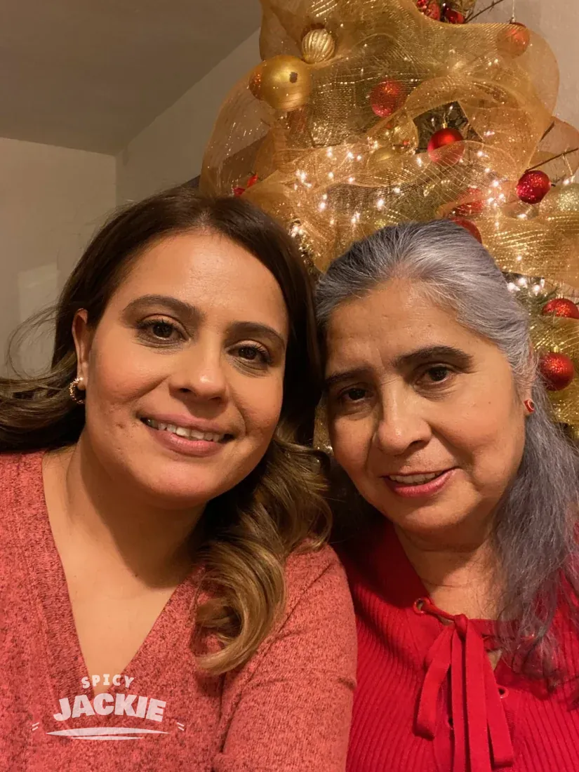 Jackie and a loved one smiling beside a decorated tree