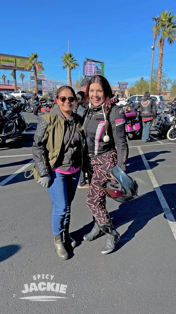 Jackie and a friend standing among motorcycles on a sunny day