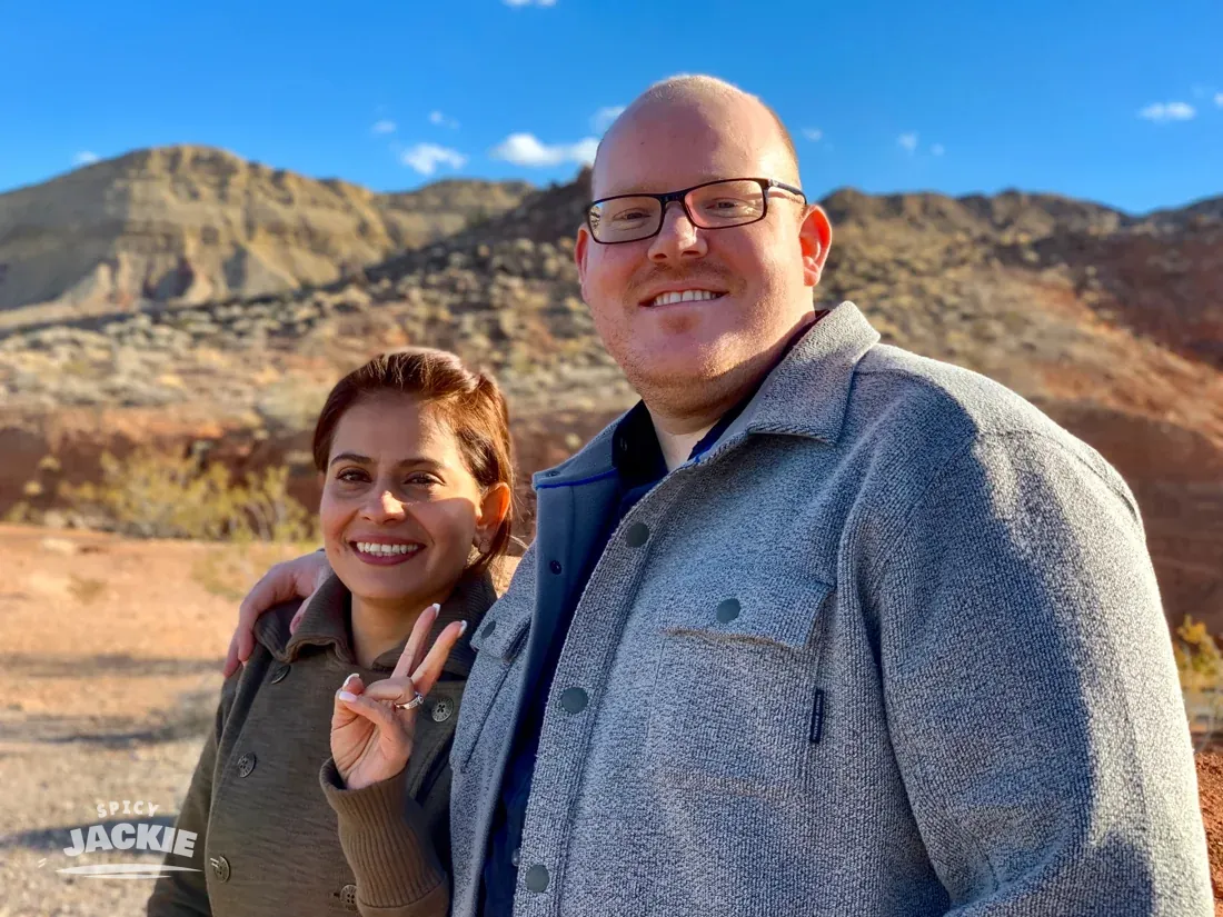 Jackie and a companion smiling in front of desert cliffs