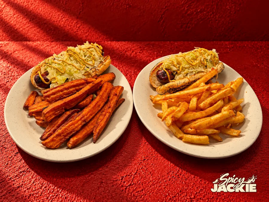 Two white plates of sausage rolls, one with sweet potato fries and one with regular fries